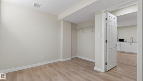 Spacious room featuring wood-finish flooring and a closet with wire shelving - 14125 30 Street, Edmonton, AB - Indoor Photo Showing Other Room