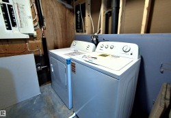 Dedicated utility area featuring a washer and dryer unit, exposed wood paneling, and a visible electrical panel - 