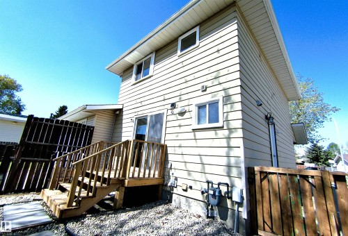 Rear exterior featuring light-toned horizontal siding and a wood deck with stairs - 14125 30 Street, Edmonton, AB - Outdoor