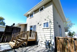 Rear exterior featuring light-toned horizontal siding and a wood deck with stairs - 