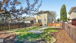 Expansive rear yard featuring a manicured lawn, established landscaping, and a wooden privacy fence - 