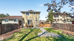 Expansive backyard featuring a manicured lawn, stone pathway, and wood privacy fencing - 