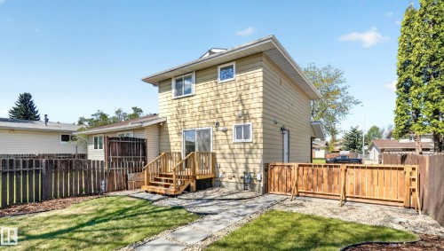 Rear exterior featuring a two-story design with shake siding, a wooden deck with stairs, and sliding glass doors - 14125 30 Street, Edmonton, AB - Outdoor
