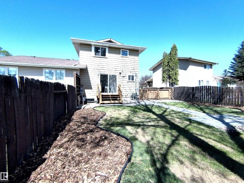 Expansive backyard featuring a manicured lawn, wood chip landscaping bed, and a wooden fence - 14125 30 Street, Edmonton, AB - Outdoor