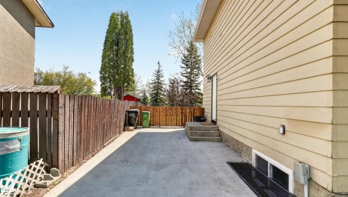 Concrete driveway alongside the property, featuring a wood fence and vinyl siding - 14125 30 Street, Edmonton, AB - Outdoor With Exterior