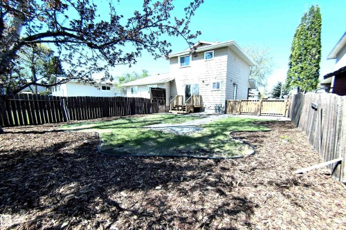 Expansive backyard featuring a manicured lawn, wood chip landscaping, and full privacy fencing - 14125 30 Street, Edmonton, AB - Outdoor
