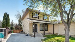 Two-story residence featuring light-colored siding, a covered entry porch, and dark trim details around windows and the front door - 