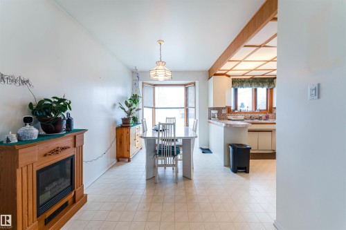 Open concept dining area featuring an ornamental wood-finish fireplace, bay window, and ceramic tile flooring - 13231 74 Street, Edmonton, AB - Indoor With Fireplace