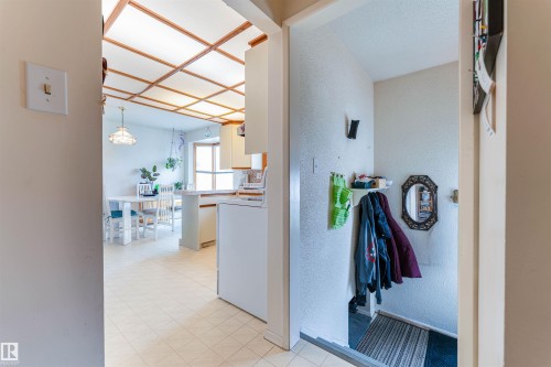 The main living area features a coffered ceiling, a dining space with a window, and a kitchen with white cabinetry and a built-in oven - 13231 74 Street, Edmonton, AB - Indoor