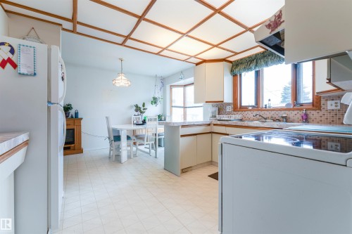 Kitchen featuring white cabinetry, tile backsplash, laminate countertops, and a full-size electric range - 13231 74 Street, Edmonton, AB - Indoor