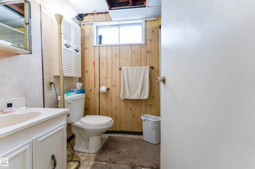 Bathroom featuring a white vanity with integrated sink, white toilet, and wood-finish wall paneling - 13231 74 Street, Edmonton, AB - Indoor Photo Showing Bathroom