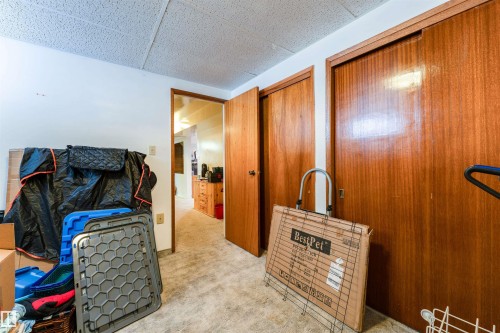 Carpeted interior space featuring a drop ceiling and a wood-finish door frame leading into another room - 13231 74 Street, Edmonton, AB - Indoor With Fireplace