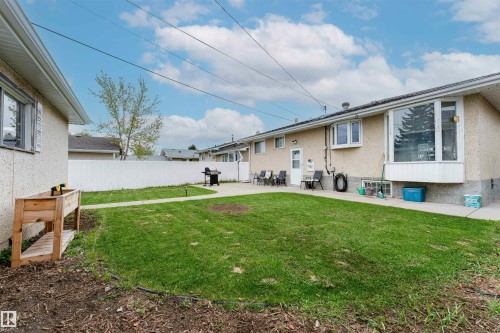Expansive backyard featuring a large concrete patio, a manicured lawn, and a white privacy fence - 13231 74 Street, Edmonton, AB - Outdoor