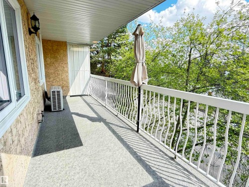 Balcony featuring a textured exterior wall, white window frames, and decorative white metal railings - 309 10610 76 Street, Edmonton, AB - Outdoor With Exterior