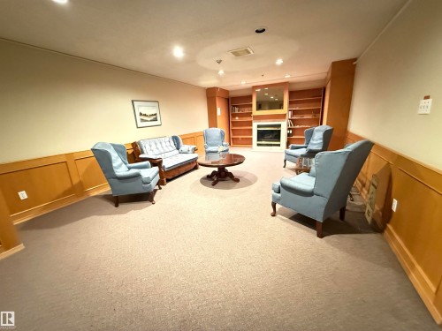 Spacious common area featuring recessed lighting, extensive wainscoting, and a built-in fireplace with an integrated mirror - 309 10610 76 Street, Edmonton, AB - Indoor With Fireplace