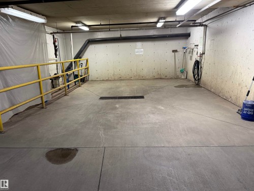 Concrete floor with central drain, equipped with overhead fluorescent lighting and exposed ceiling pipes - 309 10610 76 Street, Edmonton, AB - Indoor Photo Showing Garage