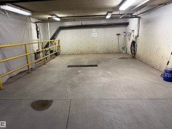 Concrete floor with central drain, equipped with overhead fluorescent lighting and exposed ceiling pipes - 