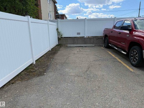 Paved parking area featuring white privacy fencing - 309 10610 76 Street, Edmonton, AB - Outdoor