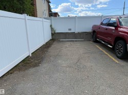 Paved parking area featuring white privacy fencing - 