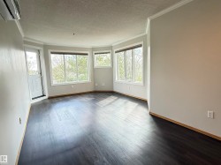 Spacious room featuring dark wood-finish flooring, a series of large windows, and a dedicated exterior door - 