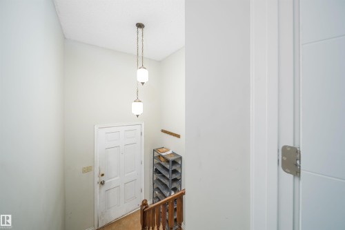 Foyer entryway featuring a multi-panel door, dual pendant light fixtures, and wood-finish flooring - 1771 37 Street, Edmonton, AB - Indoor Photo Showing Other Room