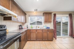 Kitchen featuring wood-finish cabinetry, tile flooring, and a sliding glass door leading to an outdoor deck - 