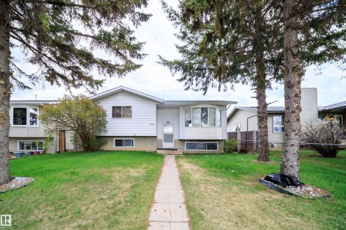 Front exterior featuring a concrete walkway, bay window, white siding, and mature trees - 1771 37 Street, Edmonton, AB - Outdoor With Facade