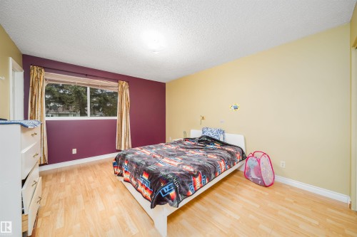 Room featuring light wood-finish flooring, a white ceiling, and a large window with white trim - 1771 37 Street, Edmonton, AB - Indoor Photo Showing Bedroom