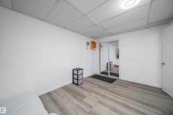 Spacious room featuring light wood-finish flooring, white walls, and a drop ceiling with recessed lighting - 