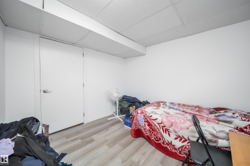 Room featuring a solid white door with a polished chrome handle, white walls, and wood-finish flooring - 1771 37 Street, Edmonton, AB - Indoor Photo Showing Bedroom