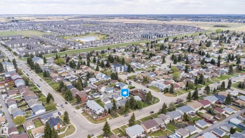 Aerial perspective of a residential neighborhood featuring established homes, mature trees, a structured street grid, and a central pond visible in the distance - 1771 37 Street, Edmonton, AB - Outdoor With View