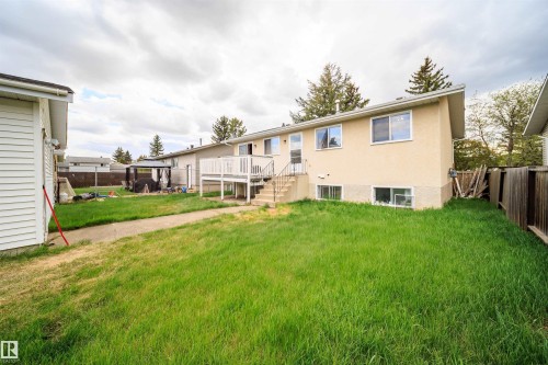 Expansive rear yard featuring a grass lawn, a wood deck with white railings, and a concrete pathway - 1771 37 Street, Edmonton, AB - Outdoor With Exterior
