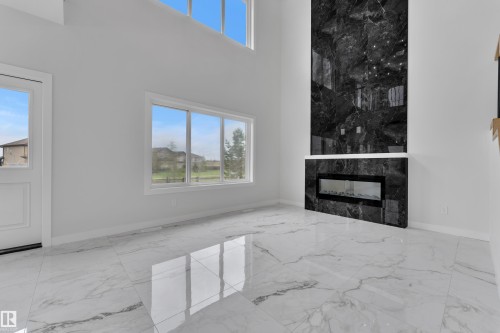 Statement fireplace featuring dark marble-look paneling and an integrated linear electric fireplace - 12623 44 Street, Edmonton, AB 