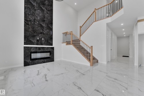 Two-story living area featuring a prominent black marble-finish fireplace wall with a linear electric fireplace - 12623 44 Street, Edmonton, AB 
