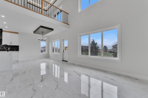 Two-story living space featuring large format marble-look tile flooring, a two-story window wall, and a lofted area with wood-finish railing - 12623 44 Street, Edmonton, AB 