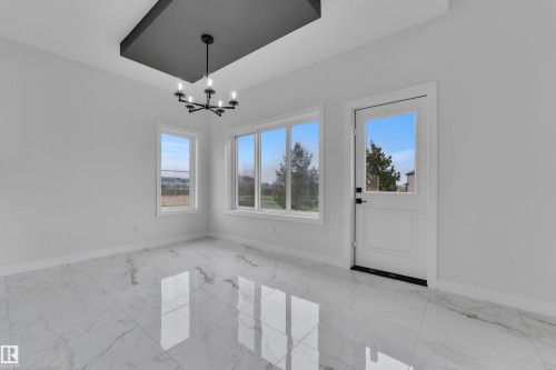 Spacious room featuring large format marble-look tile flooring, white walls, and a contemporary black chandelier - 12623 44 Street, Edmonton, AB 