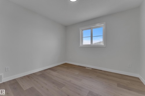 Bright room featuring light wood-finish flooring and a white trim baseboard - 12623 44 Street, Edmonton, AB 