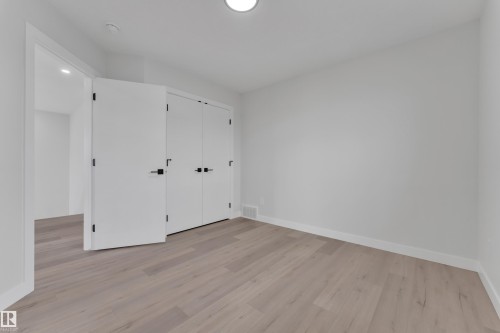 Neutral-toned room featuring light wood-finish flooring, white walls, and a white ceiling with recessed lighting - 12623 44 Street, Edmonton, AB 