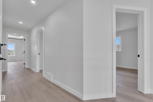 Bright interior hallway featuring light wood-finish flooring, recessed lighting, and white baseboards - 12623 44 Street, Edmonton, AB 