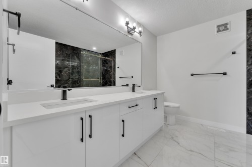 Contemporary bathroom featuring a dual-sink vanity with white cabinetry and matte black hardware - 12623 44 Street, Edmonton, AB 