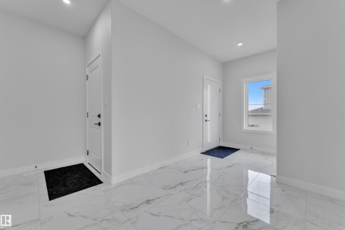 Spacious entryway featuring large format tile flooring, recessed lighting, white trim, and a window with a bright outlook - 12623 44 Street, Edmonton, AB 