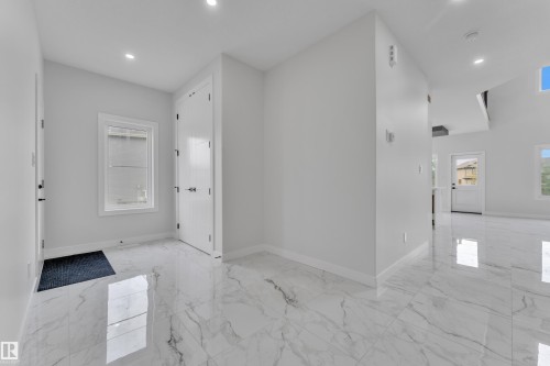 Entry foyer featuring large format tile flooring, recessed lighting, white walls, and a white paneled door - 12623 44 Street, Edmonton, AB 