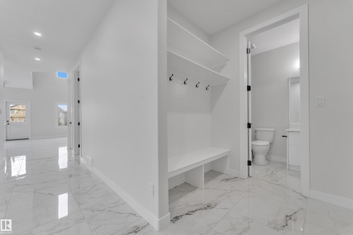 Entryway featuring large format marble-look tile flooring and a built-in bench with shelving and coat hooks - 12623 44 Street, Edmonton, AB 