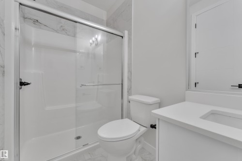 Bathroom featuring a glass-enclosed shower with white subway tile surround, white vanity with integrated sink, and large vanity mirror - 12623 44 Street, Edmonton, AB 