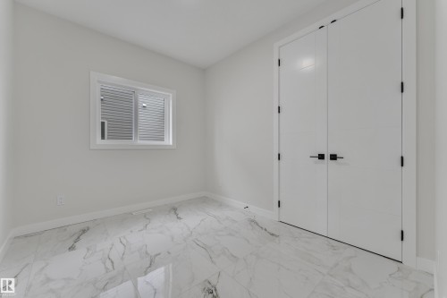 Spacious room featuring white walls, white baseboards, and marble-look tile flooring - 12623 44 Street, Edmonton, AB 