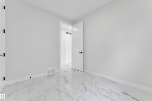 Spacious room featuring large format marble-look tile flooring, white baseboards, and bright white walls - 12623 44 Street, Edmonton, AB 