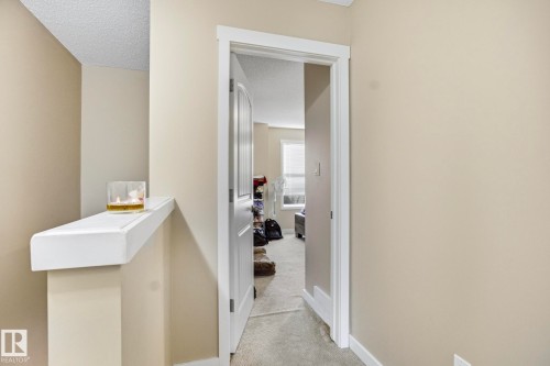 Doorway with white trim opening into a carpeted room featuring a window with horizontal blinds - 30 6075 Schonsee Way, Edmonton, AB - Indoor Photo Showing Other Room
