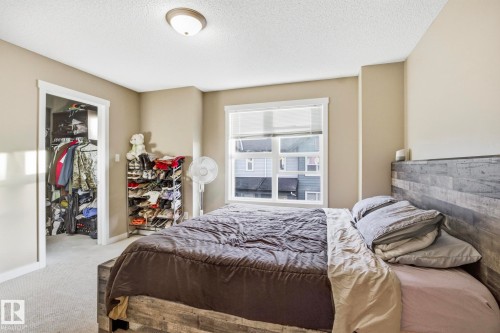 Bedroom featuring a large window with blinds, carpeted flooring, and a flush-mount ceiling light - 30 6075 Schonsee Way, Edmonton, AB - Indoor Photo Showing Bedroom