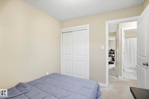 Neutral-toned bedroom featuring carpet flooring and a textured ceiling - 30 6075 Schonsee Way, Edmonton, AB - Indoor Photo Showing Bedroom