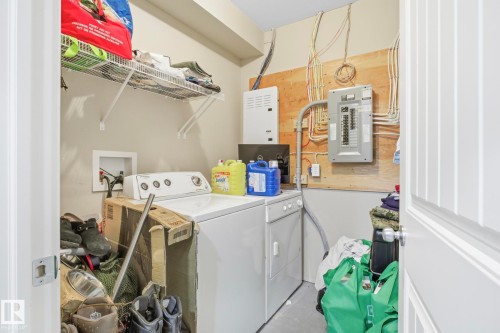 Dedicated utility space featuring washer and dryer hookups, wire shelving, and visible electrical panels - 30 6075 Schonsee Way, Edmonton, AB - Indoor Photo Showing Laundry Room